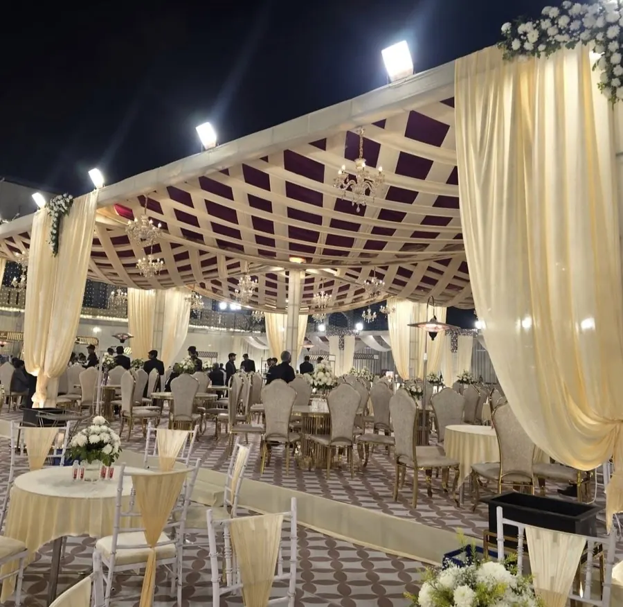 Open-air tent pavilion with ivory drapes, chandeliers and dining tables by Raju Tent & Catering Services, Bilaspur