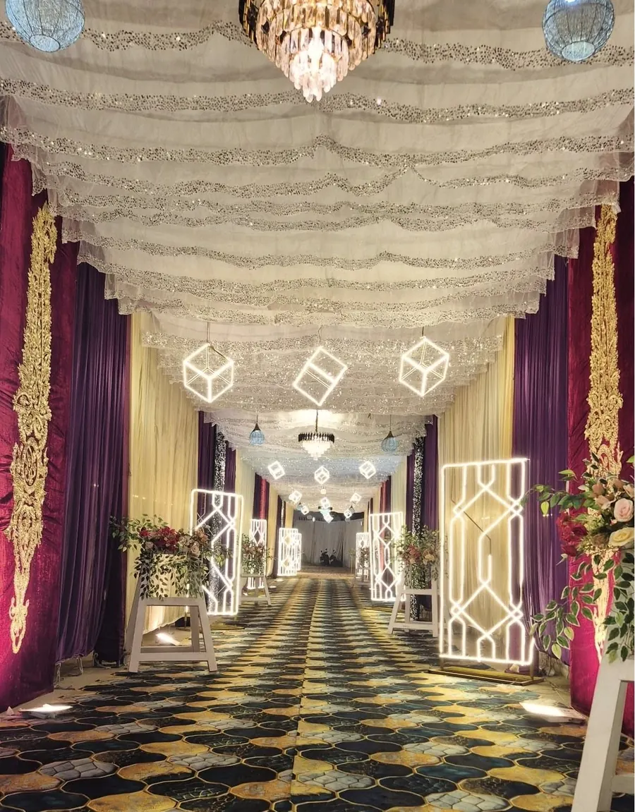 Entry tunnel with sequin ceiling drapes, velvet side curtains and chandeliers by Raju Tent & Catering Services, Bilaspur